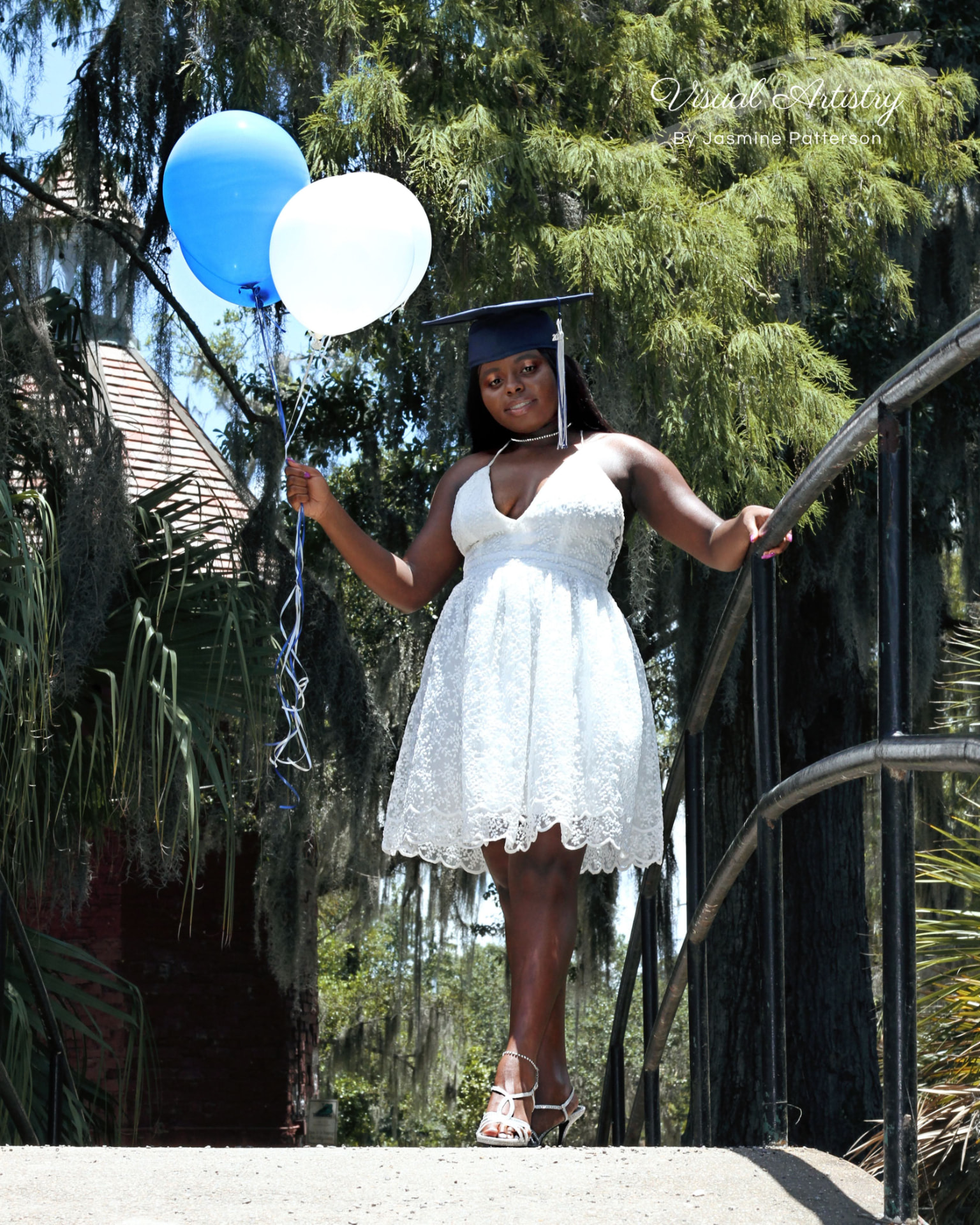 Graduate holding balloons beneath moss-draped trees